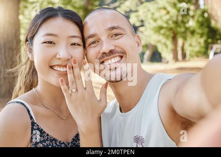 Look at what just happened. a young couple standing and taking a selfie after becoming engaged in the woods. Stock Photo