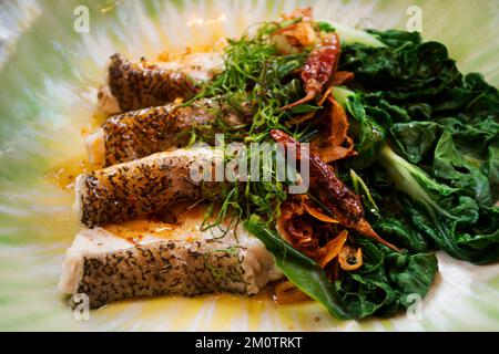 Thai chef cooking food fusion style cuisine roasted grilled fried fillet grouper fish steak with spicy sour sauce and vegetable fruit on ceramic dish Stock Photo
