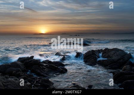 The sunset over the beach with large rocks Stock Photo