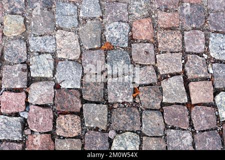 Old dark color paving cobblestone from rough blocks as background top view close up Stock Photo