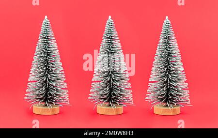 Group of Christmas artificial trees on red background close-up Stock Photo