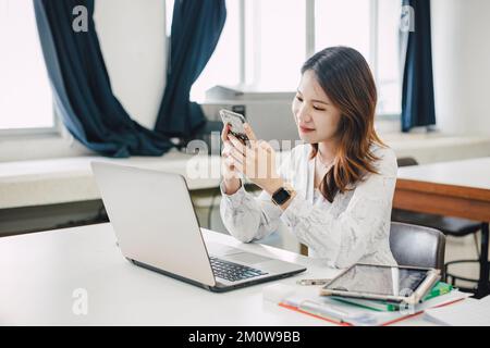 oung and beautiful asian business woman working on laptop and smartphone in office. Stock Photo