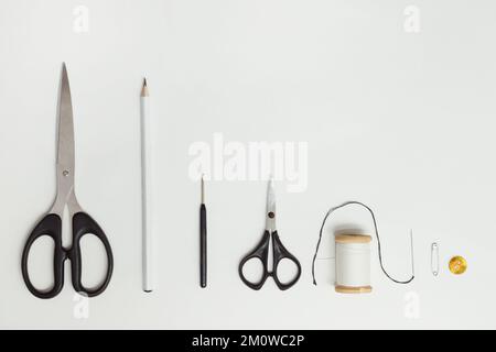 Scissors and sewing supplies on white desk. Sewing and knitting tools on white background, needlework concept. Top view on white Stock Photo