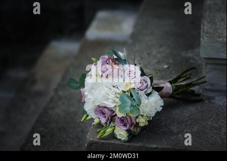 A pair of gold wedding rings on a bride's bouquet with colorful flowers. Stock Photo