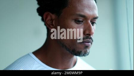 Pensive black man face, thoughtful African American man thinking looking out window Stock Photo
