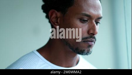 Pensive black man face, thoughtful African American man thinking looking out window Stock Photo