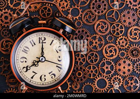 Old retro alarm clock on background with gears Stock Photo