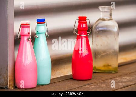 Decorative glass bottles of various bright colors with airtight stoppers on a wooden surface Stock Photo