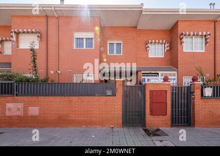 Facades of single-family houses in brown brick with metal bars and doors painted in gray Stock Photo