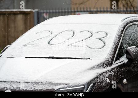 Windscreen wipers and a snow covered car, front view, 2023 inscription. handwritten on snowy window Stock Photo