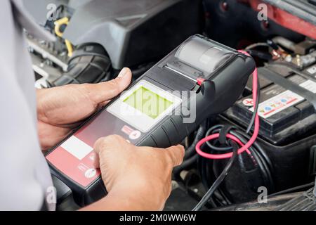 mechanic use voltmeter checking voltage of car battery in car service centre Stock Photo