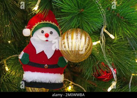 Santa Claus with Golden Ball Ornament Hanging on a Glittering Christmas Tree Stock Photo