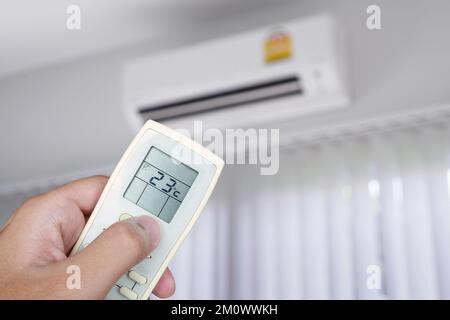 Hand using remote control with air conditioner in the room Stock Photo