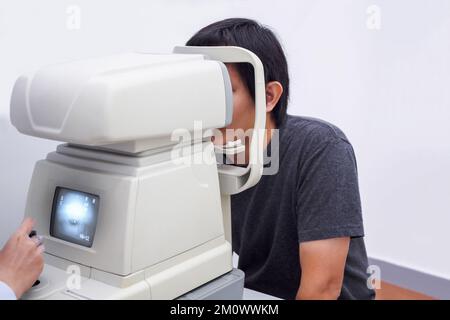 Young handsome asian man take eye exam with optical eye test machine Stock Photo