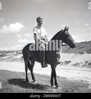 1950s, historical, a man on a horse on flat ground near a beach. Stock Photo