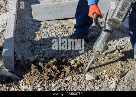 Construction road workers using jackhammer digging concrete surface Stock Photo