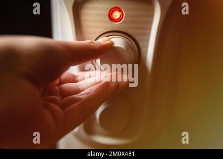 Man adjusting the oil electric heater on at home. Cold winter, economic crisis concept.  Stock Photo