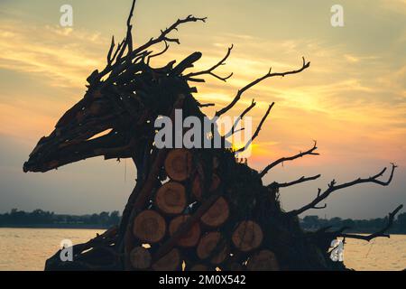 Wooden sculpture on background of sunset. Ancient totem sculpture on banks of river.. Stock Photo