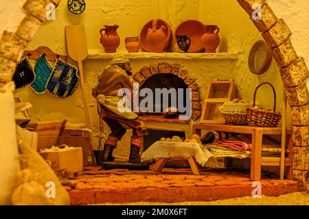 Baker taking bread out of the oven, in a portal of Bethlehem. Stock Photo