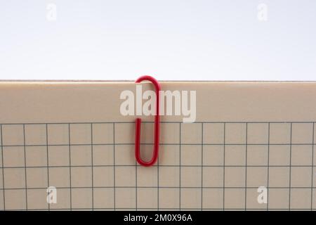 Colored paper clip on a checked notebook page Stock Photo
