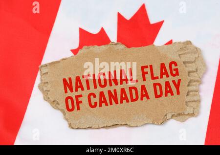 Holidays in Canada. Against the background of the flag of Canada lies cardboard with the inscription - National Flag of Canada Day Stock Photo