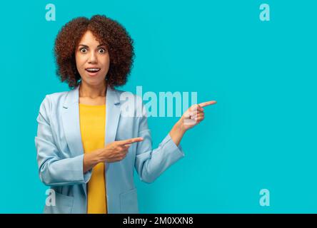 African American woman office worker in jacket pointing empty space ad isolated on blue color background, copy space Stock Photo