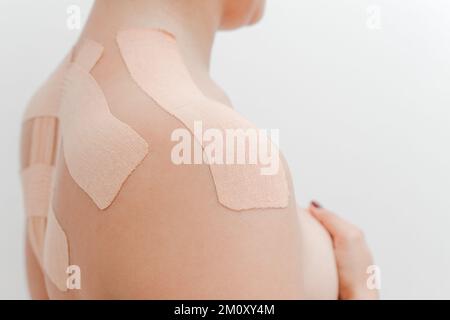 Women's body with kinesio tape on the back and shoulders. Kinesiology taping concept. White background. Close-up view Stock Photo