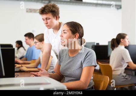 Schoolboy using computer and teacher helping to him in class room Stock Photo