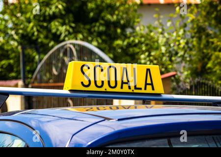 A closeup view of a driving school sign in Romanian placed on top of carScoala - School Stock Photo