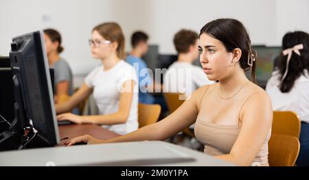 Concentrated Latin female student using PC and studying computer ...