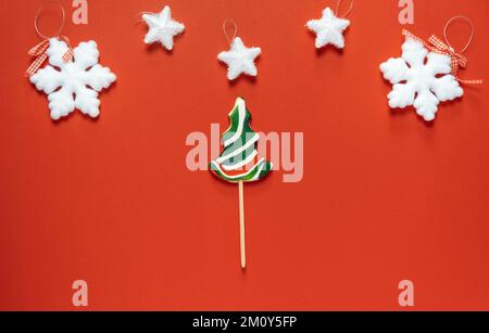 Christmas or winter composition. Frame made of snowflakes and candy trees on a red background. Christmas, winter, new year concept. Stock Photo