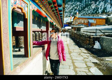 A tourist girl spins a bronze prayer drum in Himalayas, Nepal - mar, 2022. High quality photo Stock Photo