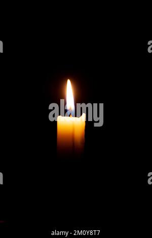 A burning candle on a black background in a dark room. Stock Photo