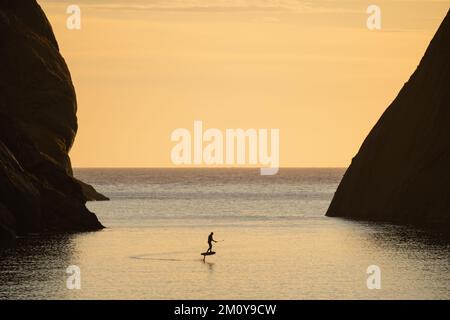 E-foil rider riding in fjord, Nusfjord, Lofoten Islands, Norway Stock Photo