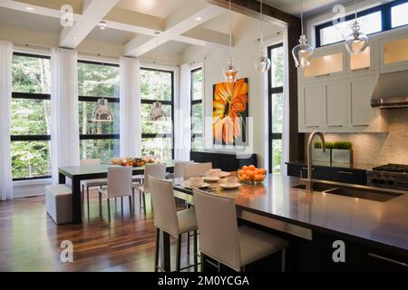 Island and dining table in opulent open concept kitchen dining room area inside upscale home. Stock Photo