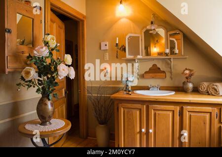 Antique wooden vanity and mirrors on shelf in rustic bathroom inside 1977 built replica of old 1800s Canadiana cottage style log home. Stock Photo