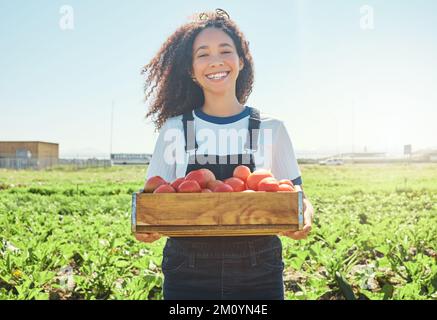 Shes proud of her produce. a female farmer holding a crate of freshly harvested tomatoes. Stock Photo