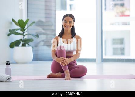 Yoga has completely transformed my life. Portrait of a sporty young woman sitting on an exercise mat in a yoga studio. Stock Photo