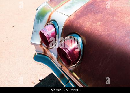 Vintage scene of red taillights on a rusty American car with a chrome bumper Stock Photo