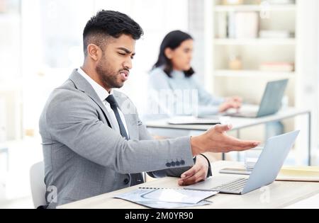 This thing keeps crashing on me all day. a young businessman looking upset while working on a laptop in an office. Stock Photo
