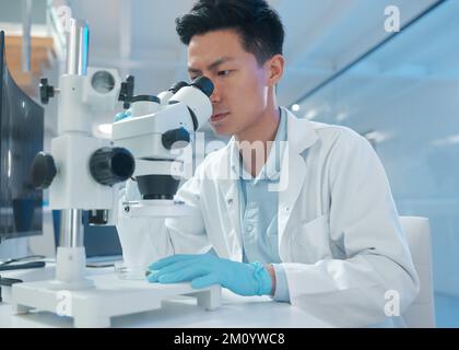 Finding a needle in a haystack. a young male technician analysing samples using a microscope. Stock Photo