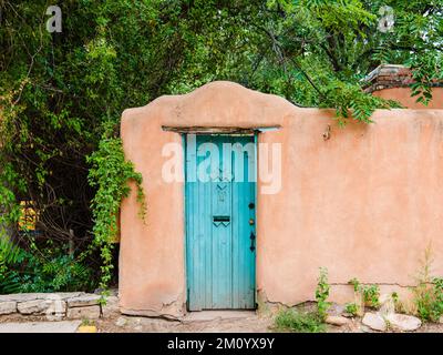 Wood turquoise colored door set in an old adobe wall in Santa Fe, New Mexico Stock Photo