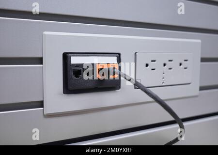 Ethernet cable plugged into wall socket. 4 socks two black two orange. cable plugged one. Stock Photo