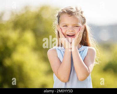 Who doesnt love surprises. a little girl looking surprised against in a park. Stock Photo