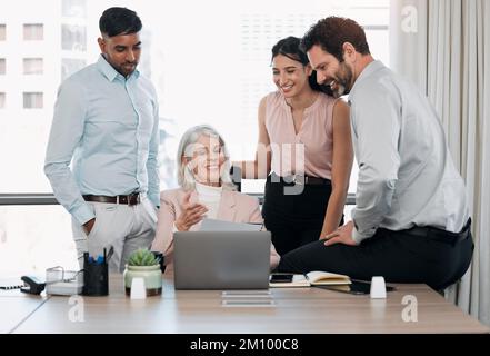 Share the teams successes. a diverse group of businesspeople using a laptop during a meeting in the office. Stock Photo