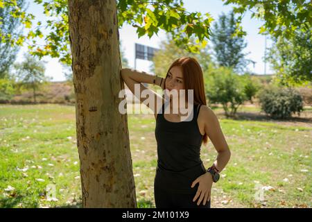 Young woman standing near tree in park Stock Photo