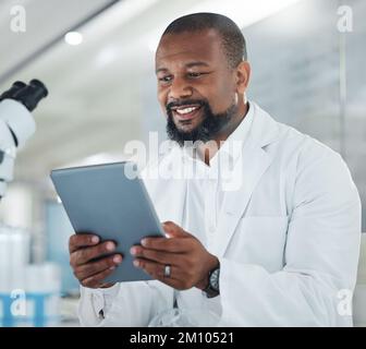 Doing some admin on top of all the experimenting. a male scientist using a digital tablet while working in a lab. Stock Photo