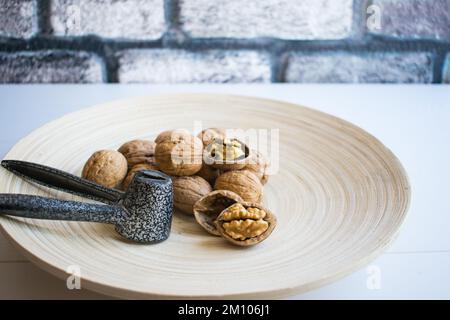 Cracked walnuts and whole walnuts in wooden plate, fresh walnut concept, healthy nuts, close-up. Stock Photo