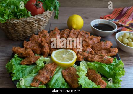 Turkish 'cig kofte”, close-up lettuce, tomato, pickle and lemon, pomegranate syrup, Turkish meatballs. Stock Photo