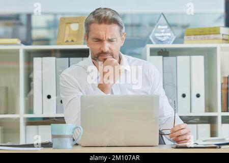 Businessman, laptop and thinking and confused in office for 404 error, internet glitch or financial report concern. Technology problem, reading Stock Photo